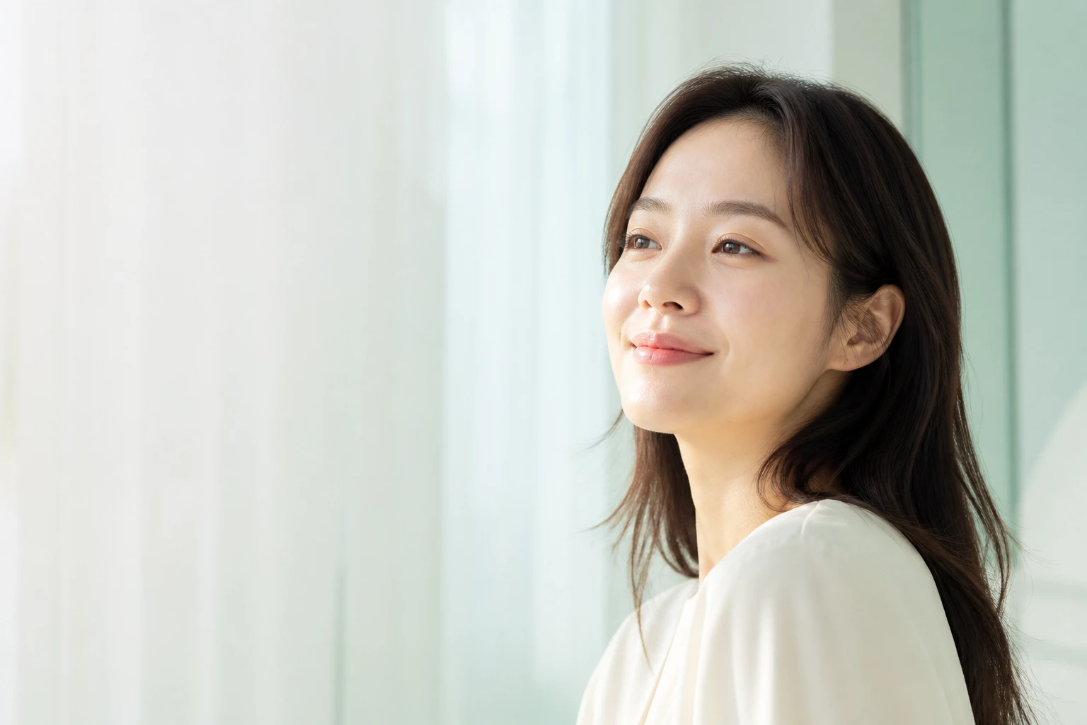 부드러운 아침빛 속에서 편안하게 미소 짓는 자연스러운 피부의 인물 콘셉트